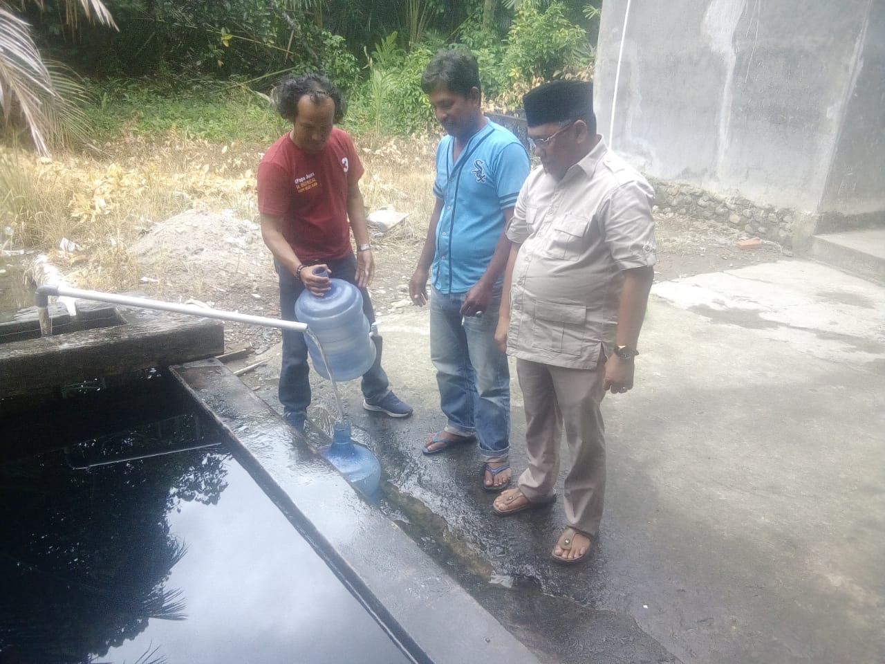 Happy Neldy saat menyaksikan warga Korong Toboh Sikaladi mengisi galonnya dengan mata air dari dalam tanah di depan teras Surau Sikaladi