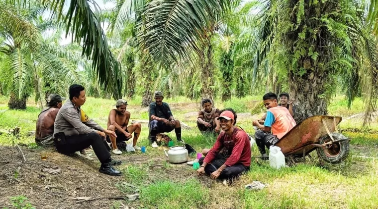 Bhabinkamtibmas Bangko Kanan, Aipda M. Rifai saat berdiskusi terkait Pilkada Damai dengan petani sawit, Jumat (13/9/2024). (Afrius)