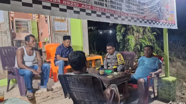 Bhabinkamtibmas Kepenghuluan Bangko Jaya, Bripka Denny Nainggolan saat menyambangi warga menggelar diskusi harmoni di malam hari demi Pilkada Damai. (Afrius)