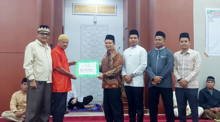 Sekretaris Tim XV, Irsyad, secara simbolis menyerahkan bantuan uang kepada pengurus Masjid Nurul Hidayah Banda Panduang (2 kiri), disaksikan Ketua Tim XV Zulfadli (kiri) Wakil Ketua Tim XV, Romi Indra Utama dan anggota Tim XV lainnya.