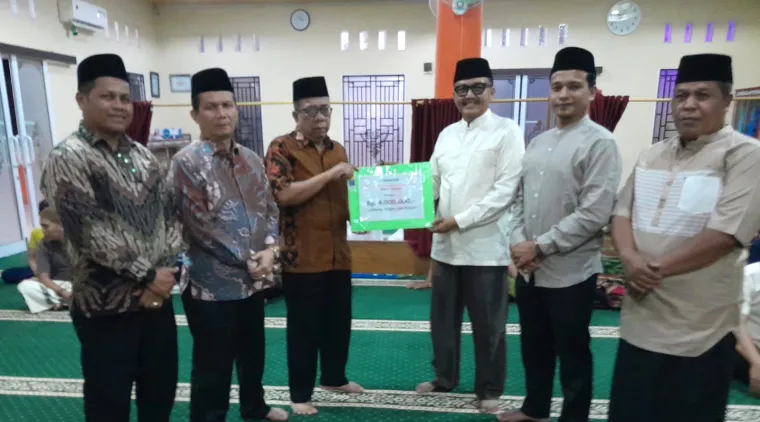 Ketua Tim XV, Zulfadli, didampingi anggota Tim XV lainnya, secara simbolis menyerahkan bantuan uang Rp 4 juta kepada Ketua Pengurus Masjid Al Muhajirin Tanah Garam, Zulmasdiawarman (3 kiri)