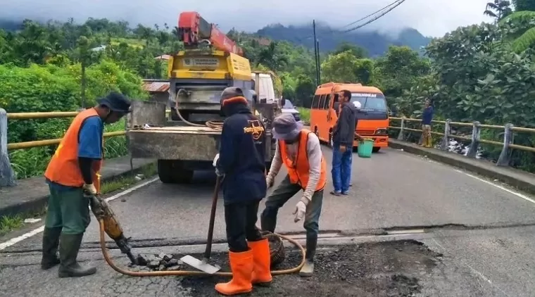 Pekerja sedang memperbaiki jalan yang rusak