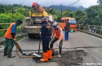 Pekerja sedang memperbaiki jalan yang rusak