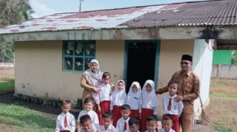 Kepala Sekolah, guru dan siswa berfoto di depan gedung bangunan bekas WC yang dijadikan ruang kelas (Foto: SDN 002)