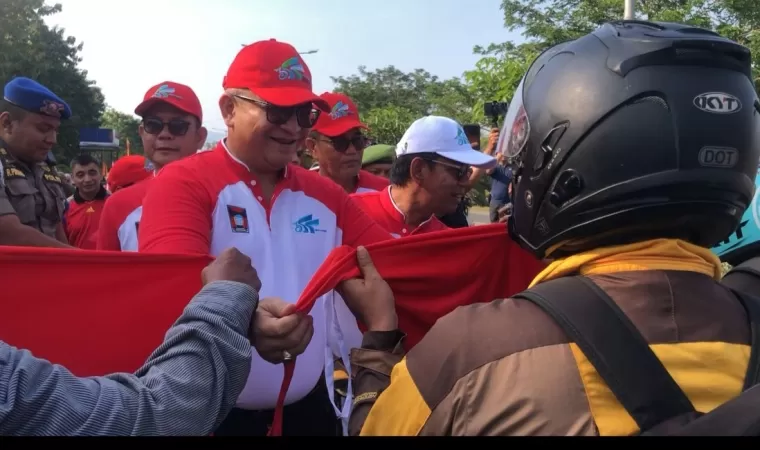 Pj Wali Kota Padang, Andree Algamar memberikan bendera merah putih kepada seorang pengendara yang melintas di depan Balai Kota Padang