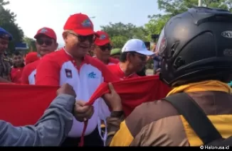 Pj Wali Kota Padang, Andree Algamar memberikan bendera merah putih kepada seorang pengendara yang melintas di depan Balai Kota Padang