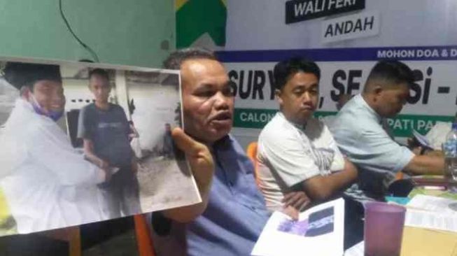 Kuasa Hukum Tri Suryadi-Taslim, Zulbahri, menunjukkan salah satu foto yang dijadikan barang bukti dugaan pelanggaran yang dilakukan Paslon 01 saat jumpa pers di Pariaman, Kamis (17/12/2020) malam. [Antara/Aadiaat M.S.]