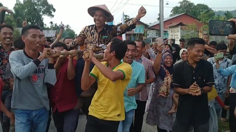 Warga sedang mengarak Juanha dari masjid pulang ke rumah tanpa menggunakan sendal dan sepatu.