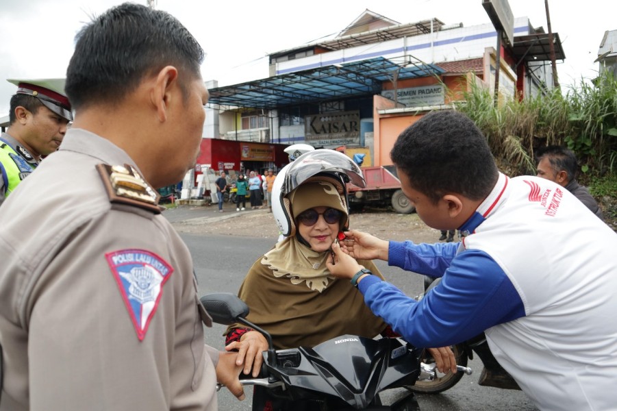 Salah seorang instruktur safety riding dari PT Hayati Pratama Mandiri bantu pengendara menggunakan helm SNI. (Foto: Honda Hayati)