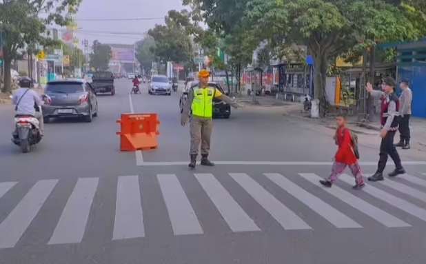 Petugas Satlinmas bantu anak sekolah nyebrang jalan. (Foto: tangkapan layar IG @satpolpppadang)