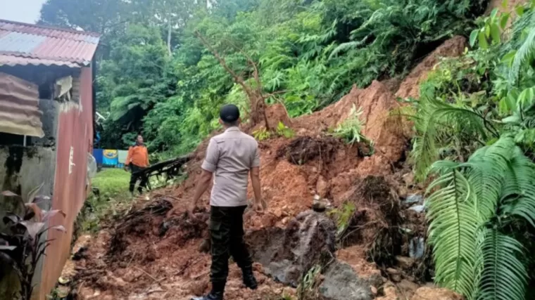 Petugas membersihkan material longsor yang nyaris menimbun rumah warga di Kota Padang, Jumat (21/6/2024). (Foto: Istimewa)