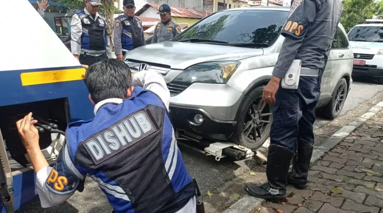 Tim Dishub Padang mengempeskan ban mobil yang parkir sembarangan