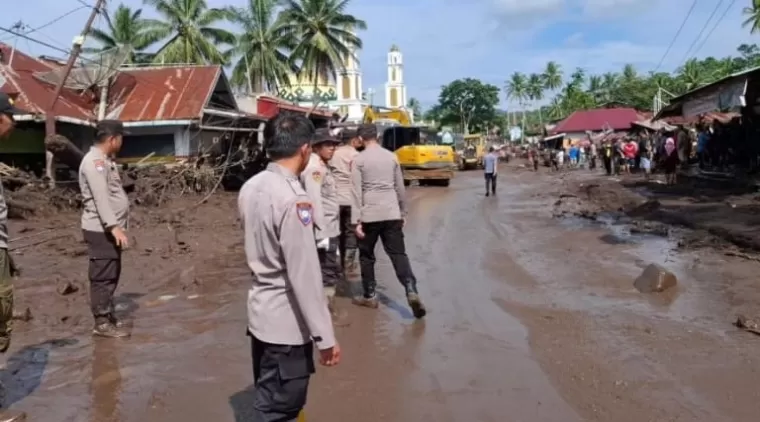 TEKS Foto: Personel Polda Sumbar membantu warga mengevakuasi material yang ada di pemukiman rumah warga di salah satu lokasi bencana banjir bandang, Rabu (15/5).(deri)