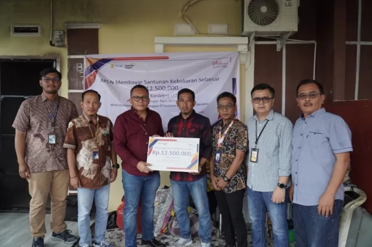 Penerima Santunan Kebakaran, Syahril (tengah, kemeja kotak-kotak merah), diapit Distribution Head IX Bank Mandiri Taspen, Tumbur Tobing (kiri, kemeja merah), dan Kepala Cabang APLN, Yusran (kanan, kemeja batik).