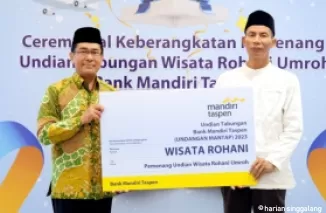 Direktur Bisnis Bank Mandiri Taspen, Maswar Purnama (kiri, baju batik) menyerahkan giant check kepada perwakilan Pemenang Undian Wisata Rohani Umroh di Jakarta sebelum memberangkatkan mereka ke tanah suci.(ist)