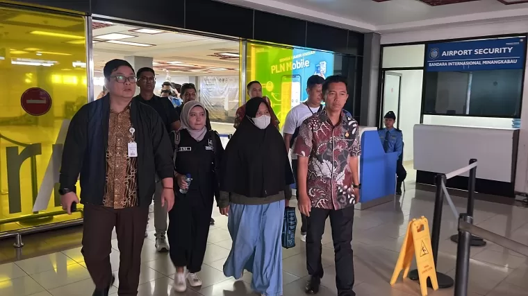 Terpidana Khuslaini (mengenakan masker) bersama tim intelejen Kejagung dan Kejati Sumbar sesampai di Bandara Internasional Minangkabau (BIM) setelah berhasil ditangkap petugas di kawasan Batam, Selasa (1/10).