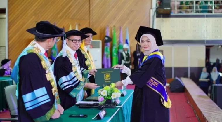 Rektor Unand, Efa Yonnedi menyerahkan ijazah kepada salah satu lulusan yang diwisuda Sabtu (23/11) di auditorium kampus tersebut. (foto: wahyu)