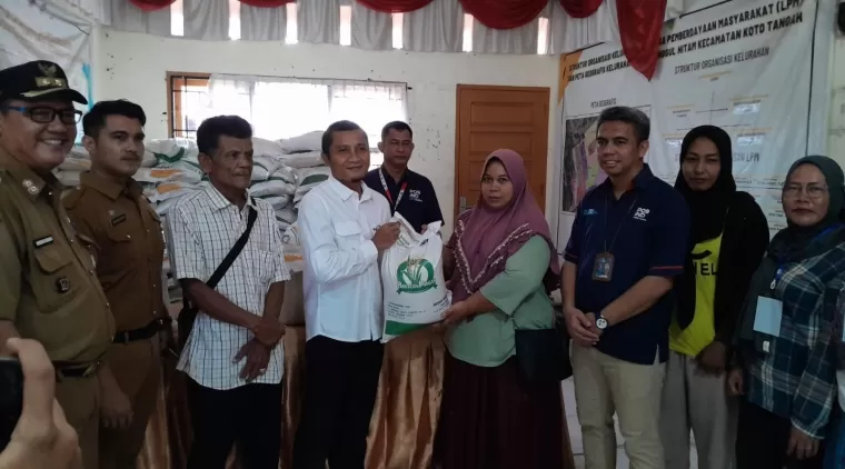 BANTUAN PANGAN - Pemimpin Perum Bulog Wilayah Sumbar, R. Darma Wijaya menyerahkan beras bantuan pangan kepada salah seorang penerima bantuan di Kelurahan Dadok Tunggul Hitam. (yuni)